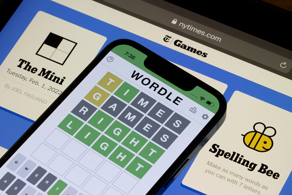 Wordle webbsida visas på dess officiella webbplats på en iPhone med New York Times Games webbsida på en iPad i bakgrunden.