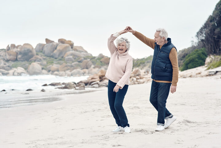 ett äldre par som dansar tillsammans på stranden
