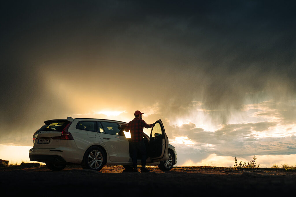 en man står vid sin bil, solnedgång