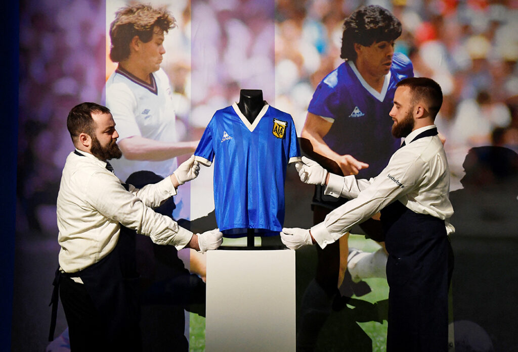 Konsthanterare poserar med tröjan som bars av den argentinske fotbollsspelaren Diego Maradona i fotbolls-VM 1986