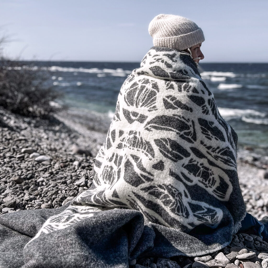 Person sitter på en strand med pläd