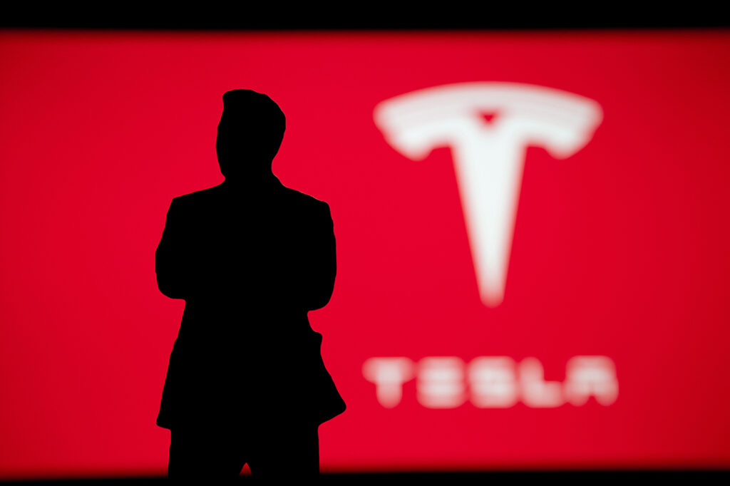 Elon Musk med Tesla logo i bakgrund