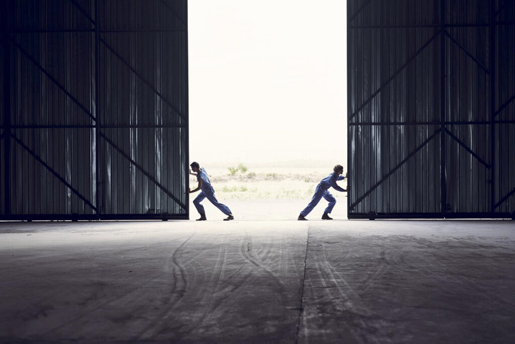 två person knuffar up pvå dörrar i en stor lada