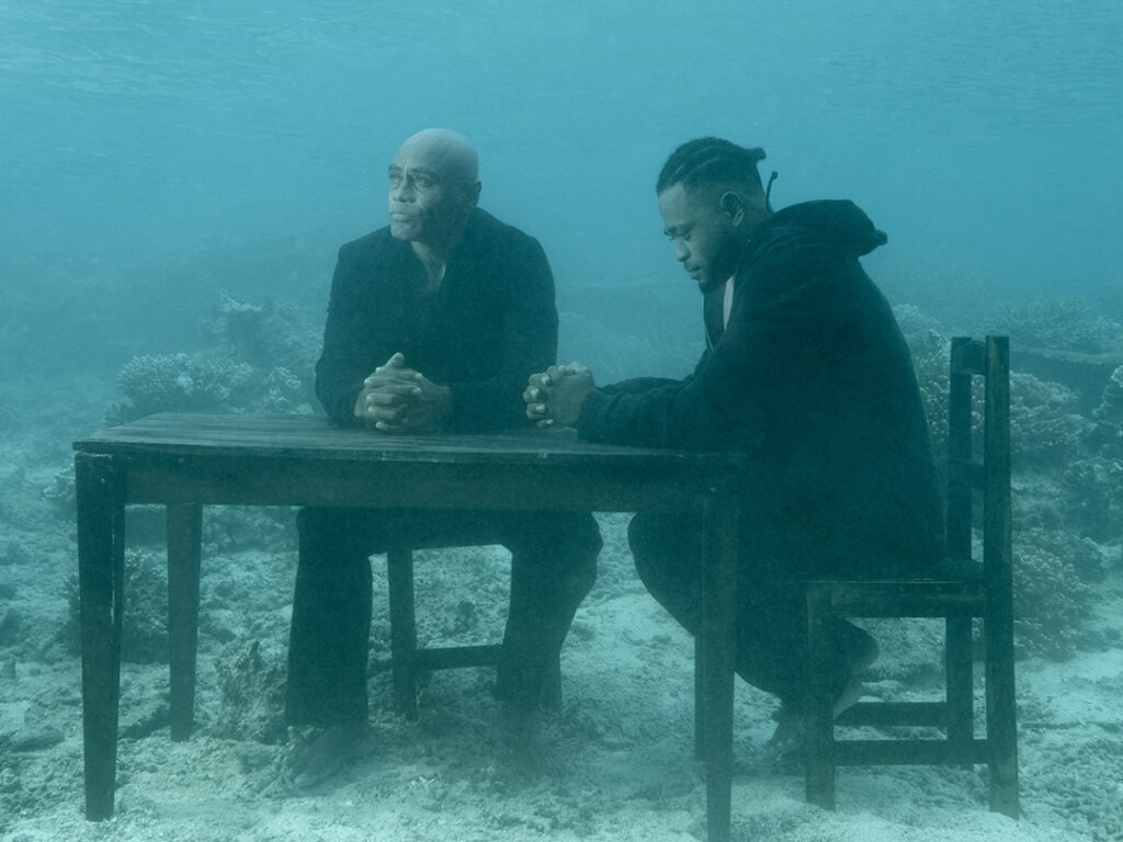 Två män sitter under ytan vid ett köksbord