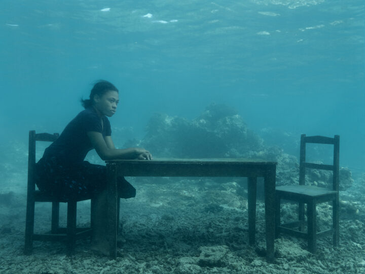 En kvinna sitter ensam vid ett bord under vattnet