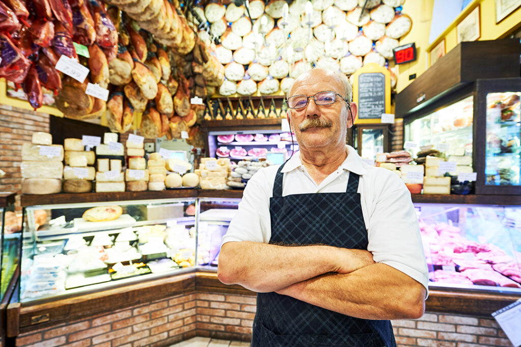 en äldre italiensk säljare i en ost o köttbutik