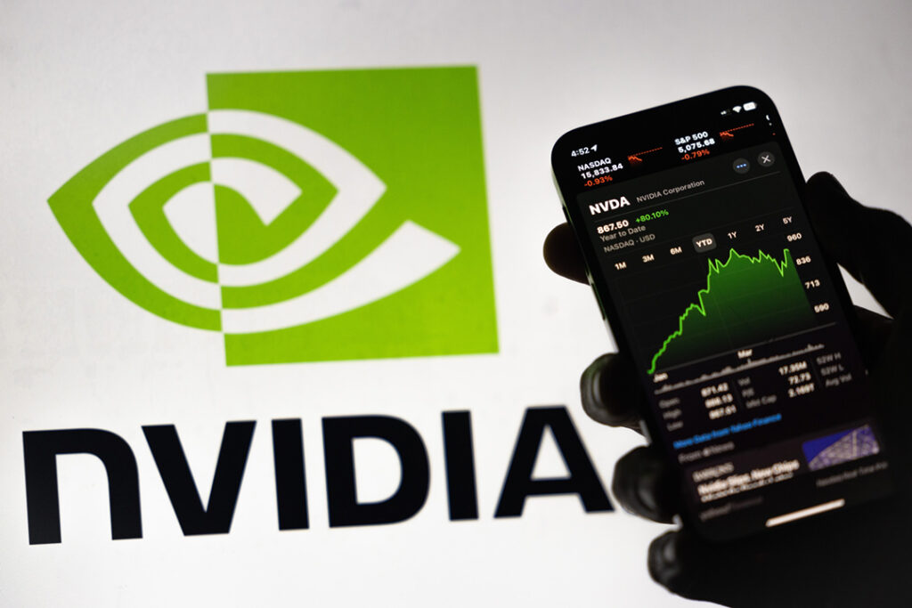  En bakgrundsbelyst hand håller en telefon och visar upp gröna stigande Nvidia-aktier