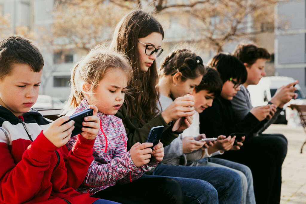 
Barn använder telefoner utomhus, begreppet barnberoende av sociala nätverk