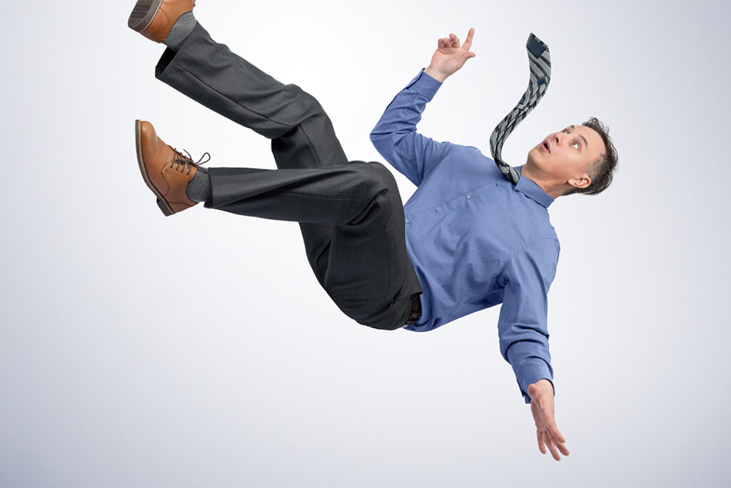 man i kontorskläder och slips faller ner på ljusgrå bakgrund