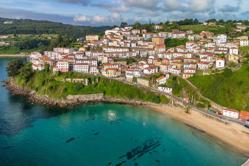 Flygfoto över den charmiga fiskebyn Lastres i Asturien-regionen, norra Spanien. En vacker kuststad inbäddad på en sluttning med utsikt över Biscayabuktens turkosa vatten.